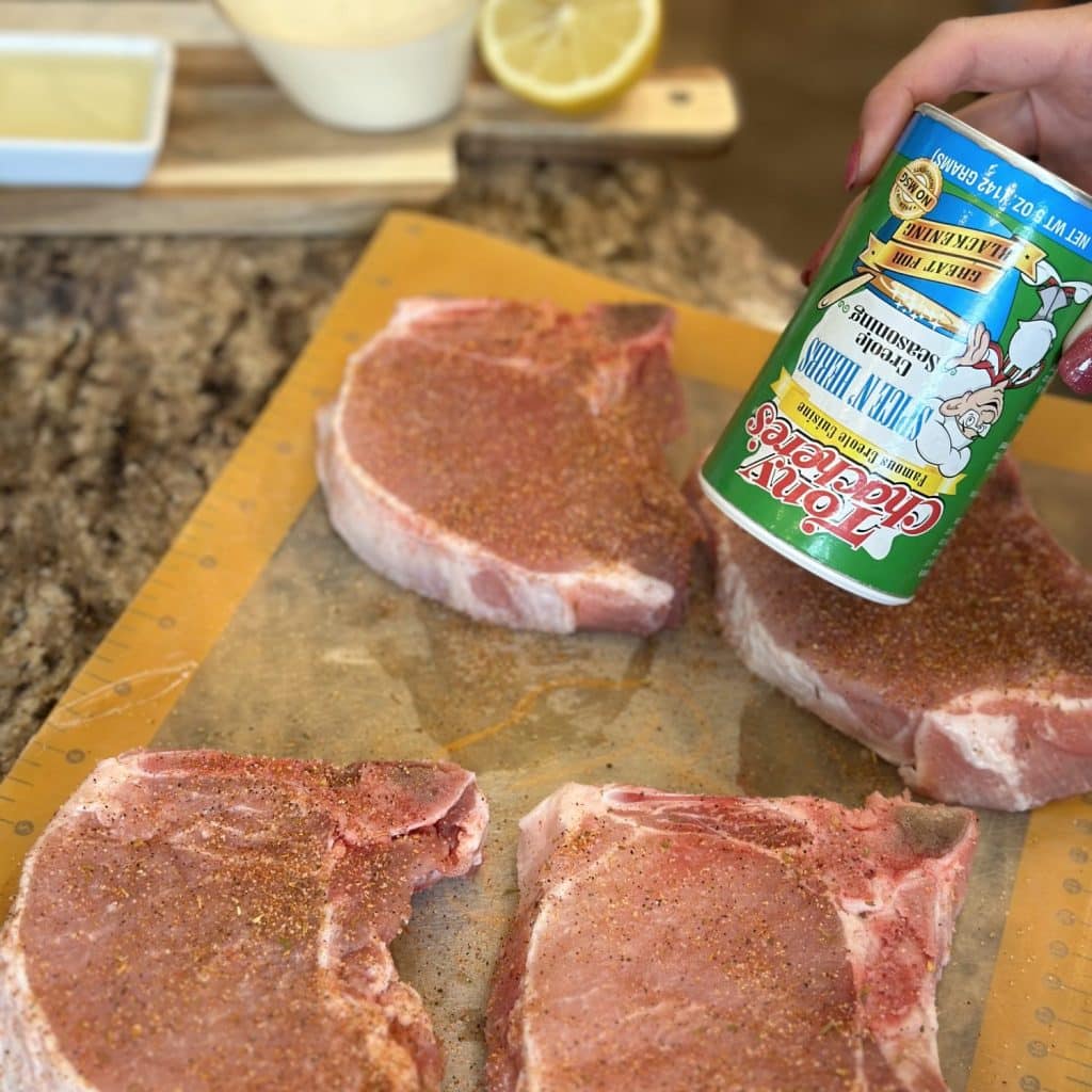 pork chops being seasoned with cajun seasoning.