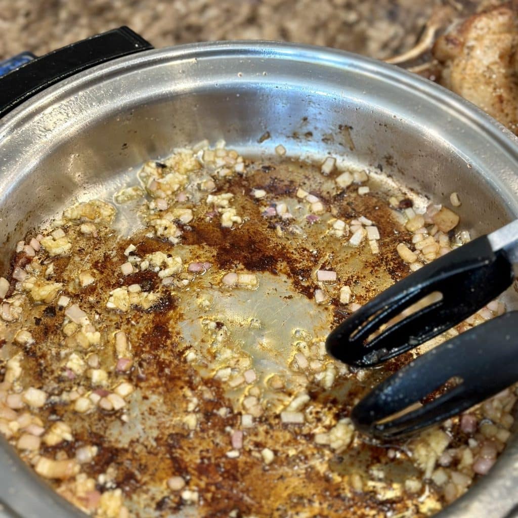 Sautéing onion and garlic in a skillet in pan juices.