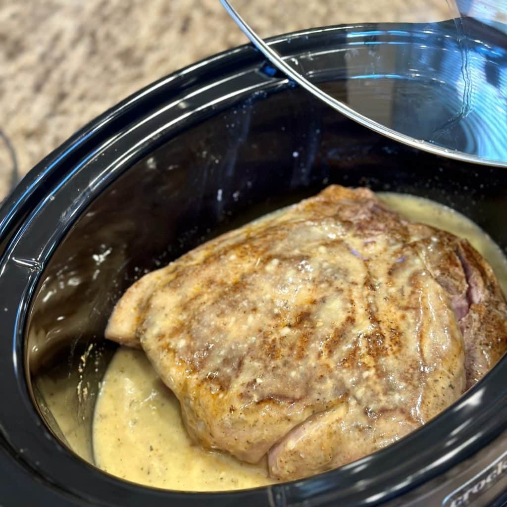 A pork butt in a crockpot with a cream of chicken and herbs gravy.