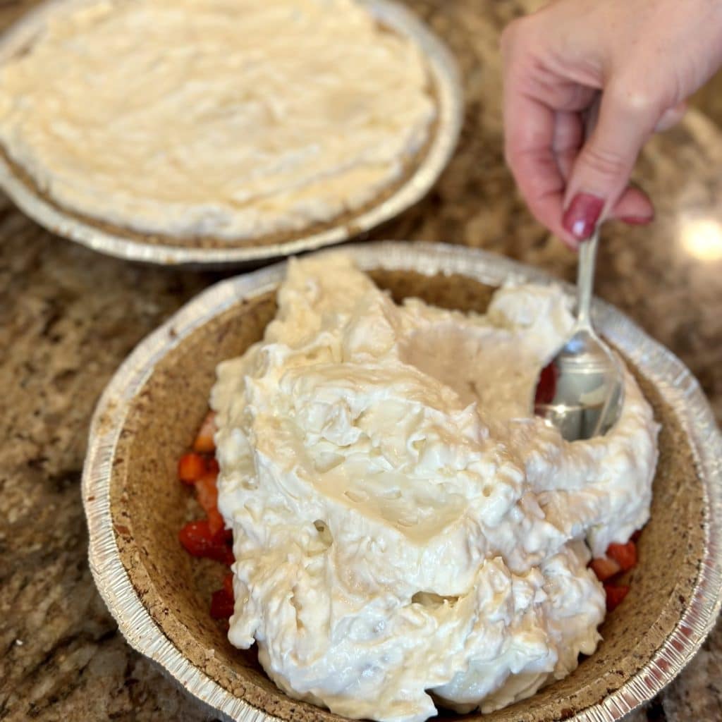 Filling being spread with a spoon in a pie crust.