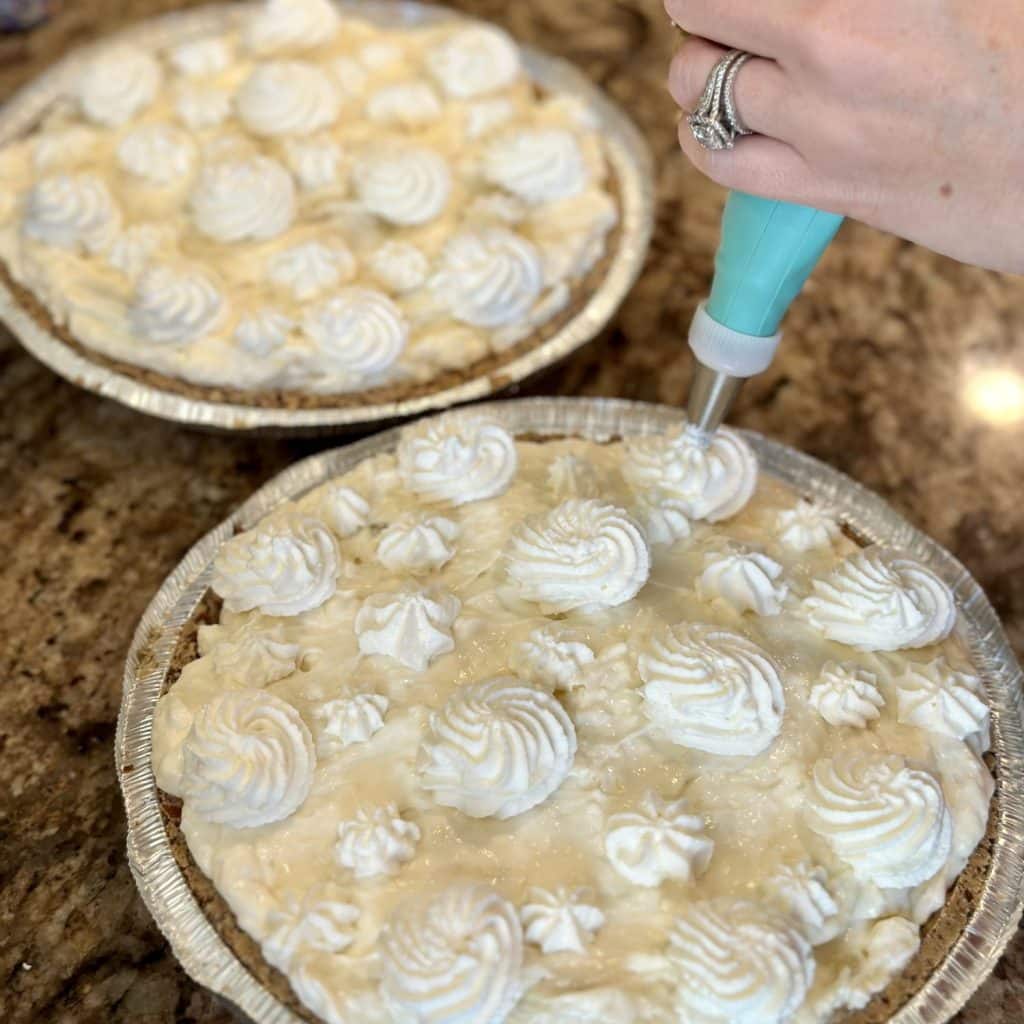 Whipped cream being piped on a pie.