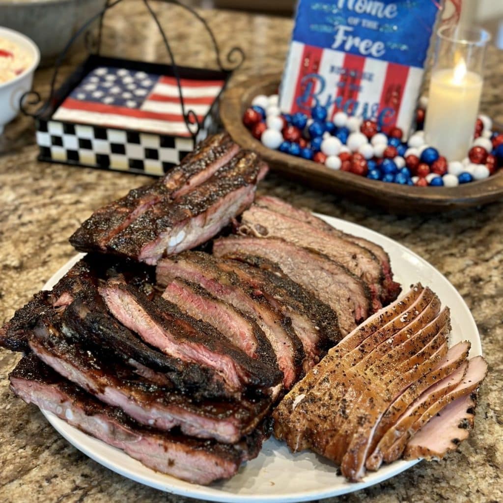 A plate of sliced brisket, turkey and ribs that were cooked on the smoker.
