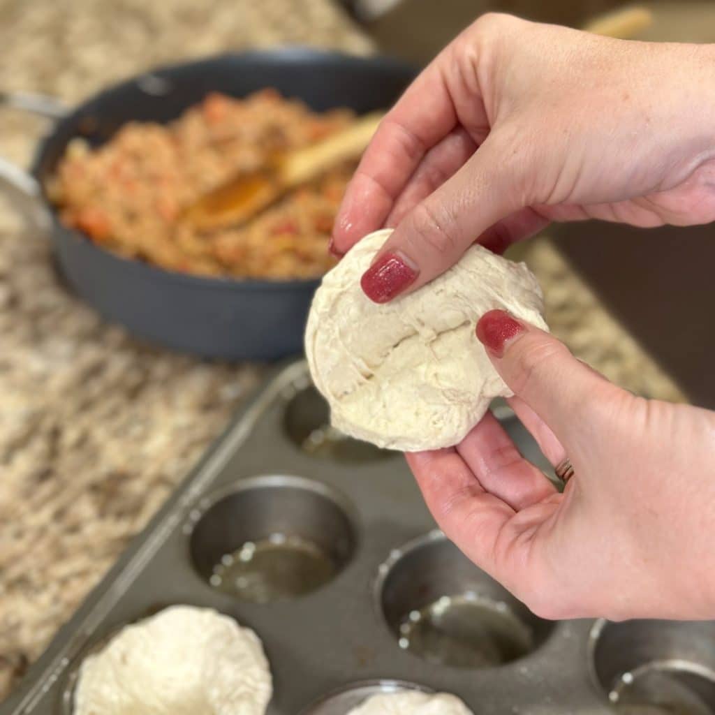 Splitting apart a refrigerated biscuit dough in half.