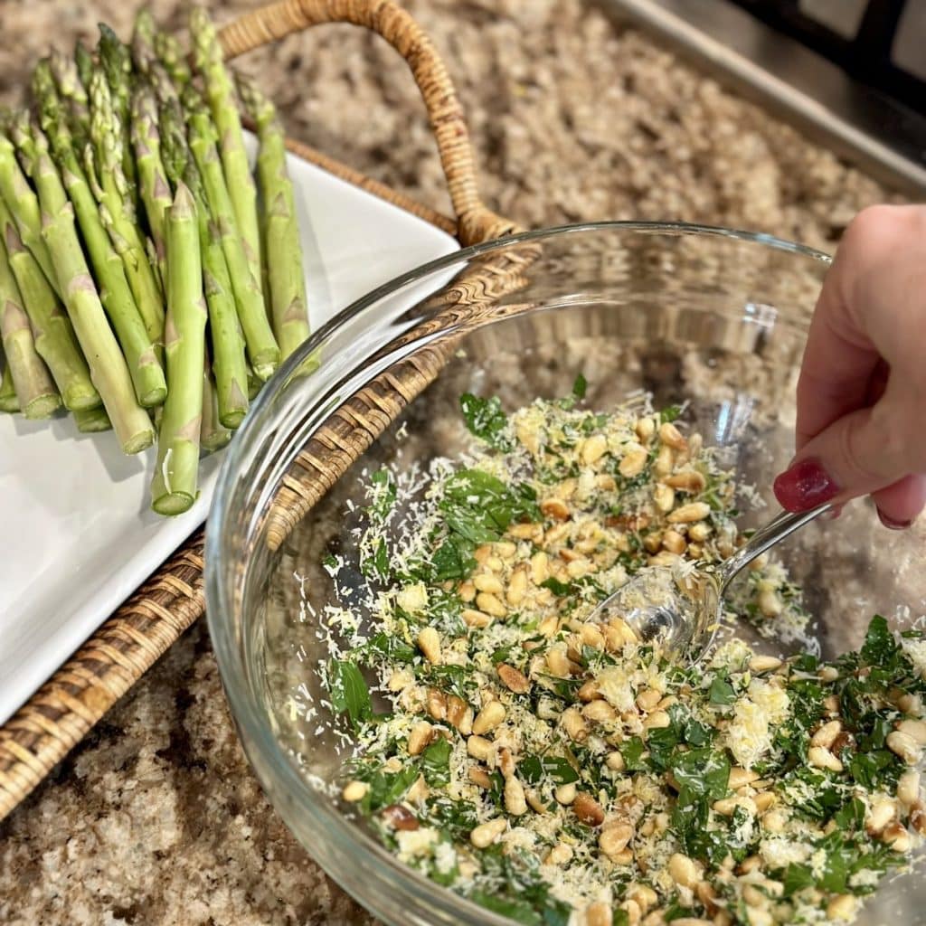 A bowl with ingredients to make gremolata: parsley, garlic, lemon zest, parmesan and pine nuts.