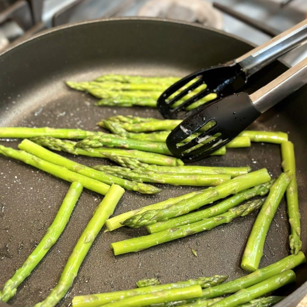 Searing asparagus in a large skillet.