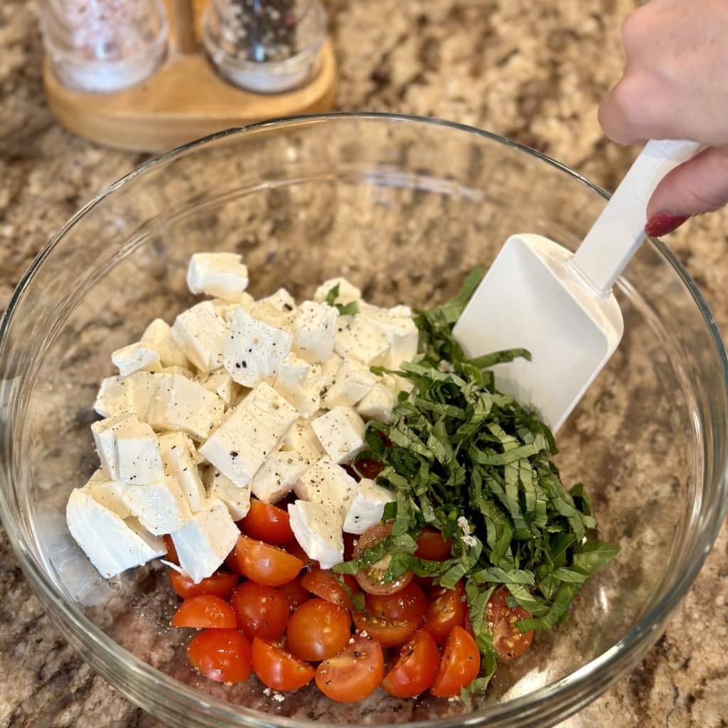 A glass bowl with tomatoes, mozzarella and basil inside.