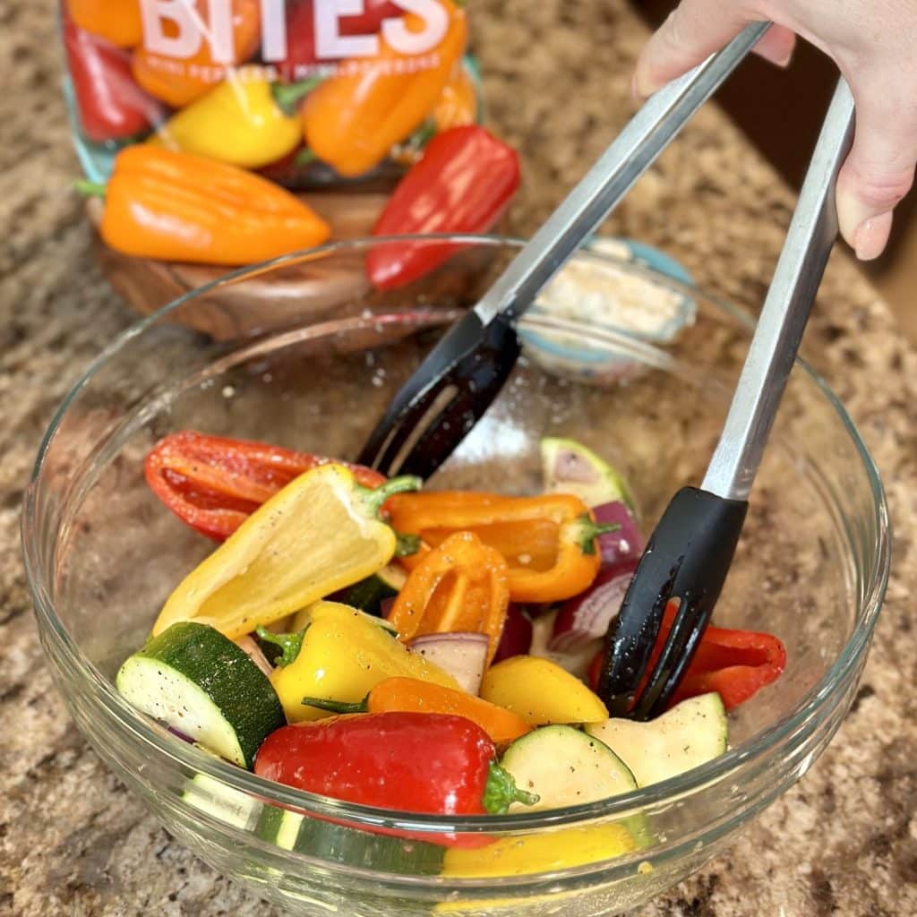 Tossing vegetables in a bowl with dressing.