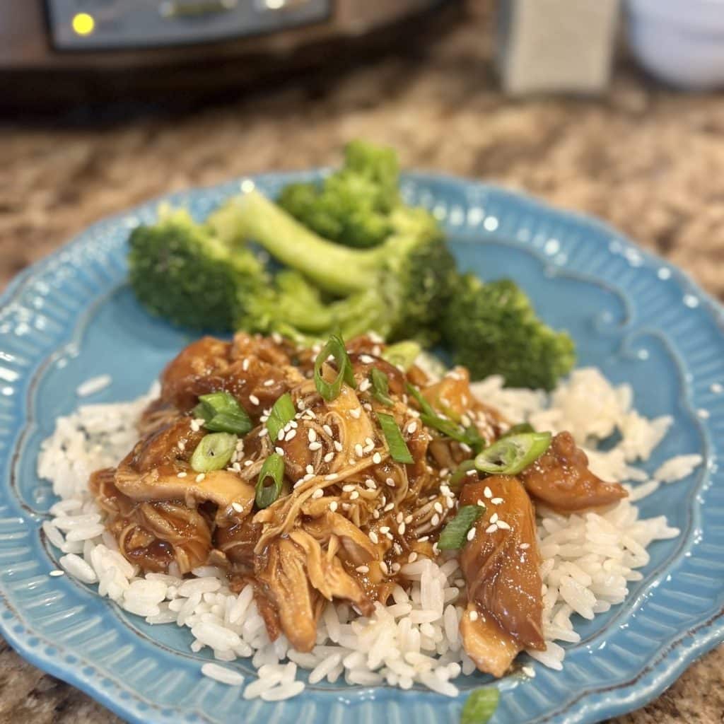 Honey garlic chicken on top of rice with steamed broccoli.