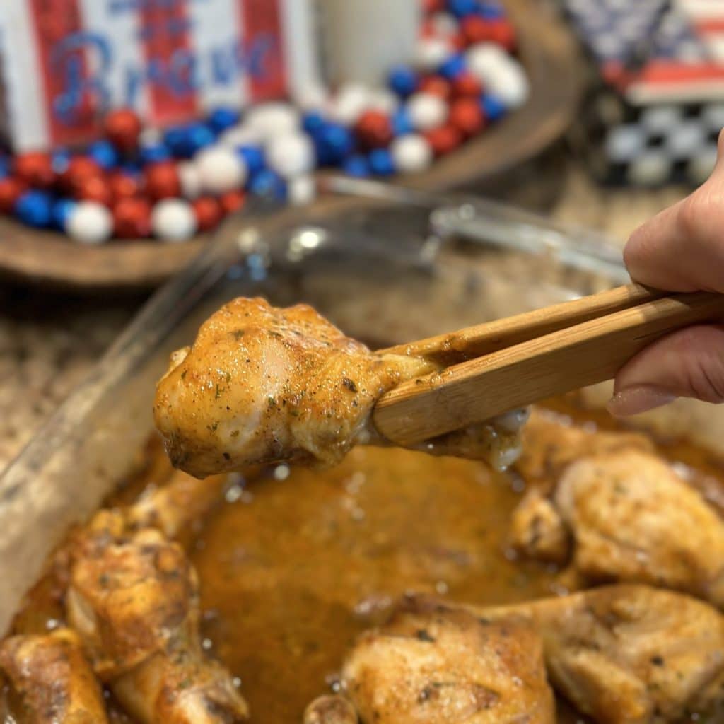 A baked drumstick being held by tongs.