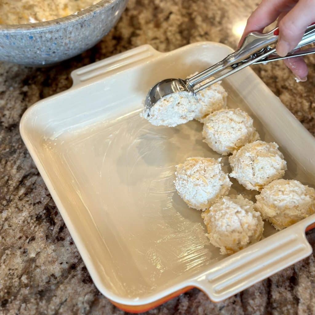 Scooping biscuit dough in a baking dish.