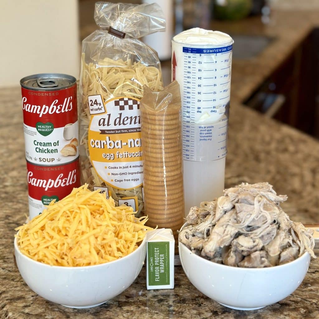 The ingredients needed to make a cheesy chicken pasta bake.