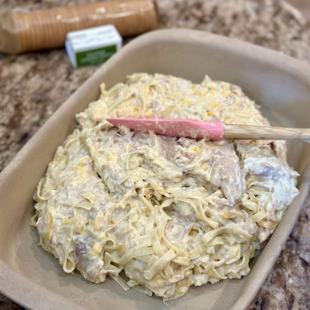 Spreading a cheesy chicken mixture in a baking dish.