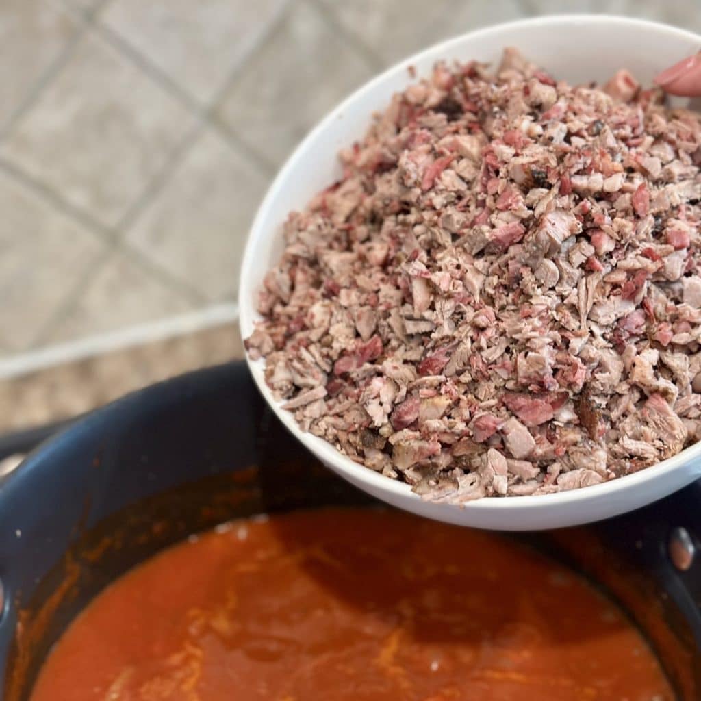 Chopped cooked brisket about to be added to a stockpot for chili.