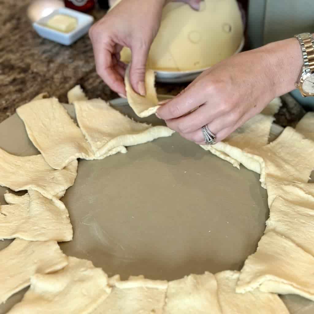 Placing crescent rolls on a pizza stone in a circle.