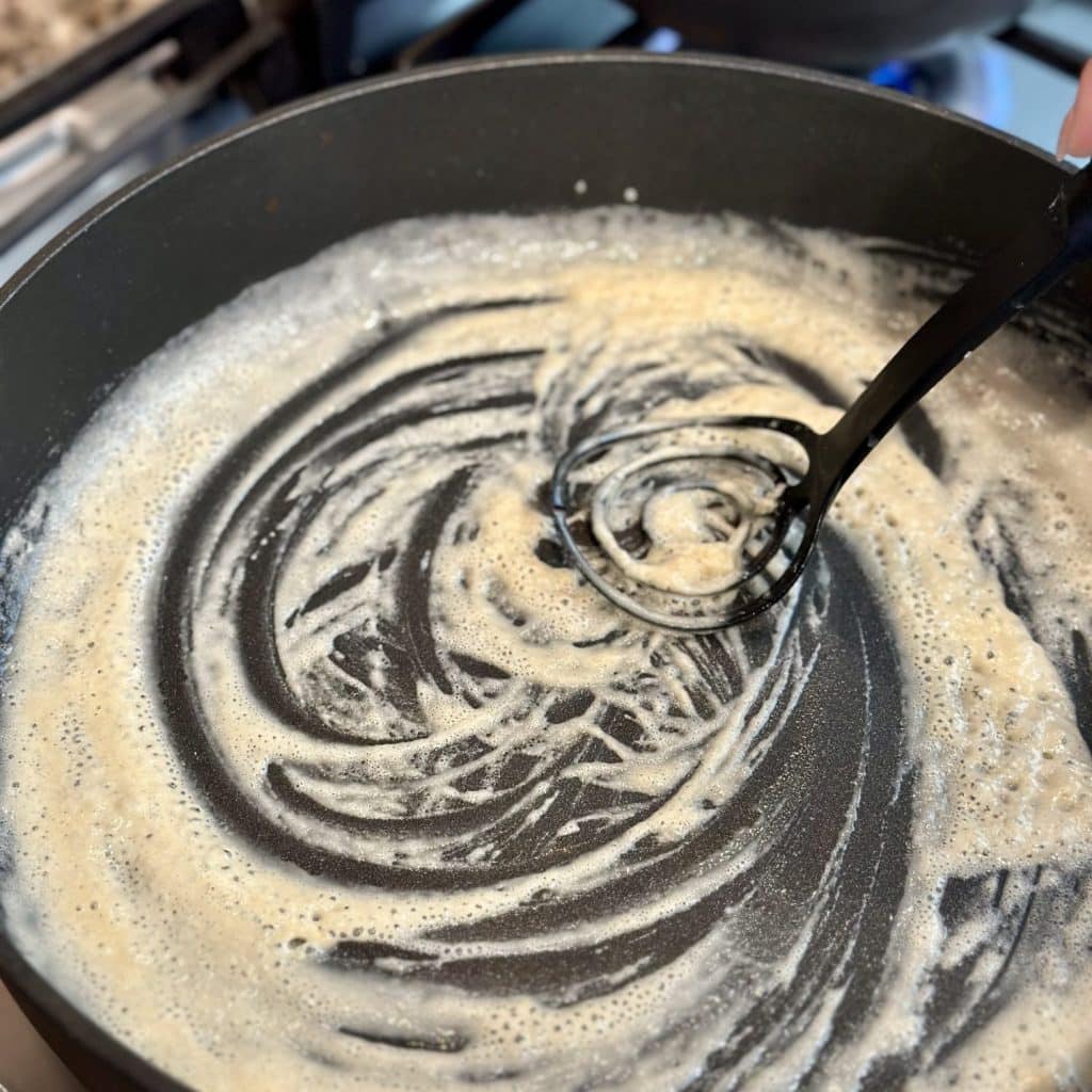 Whisking together butter and flour in a pan.
