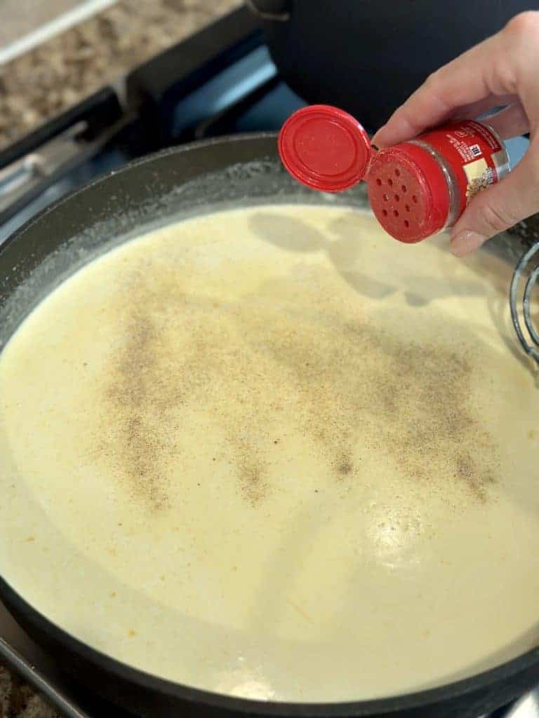 Seasoning a cheese sauce with white pepper.