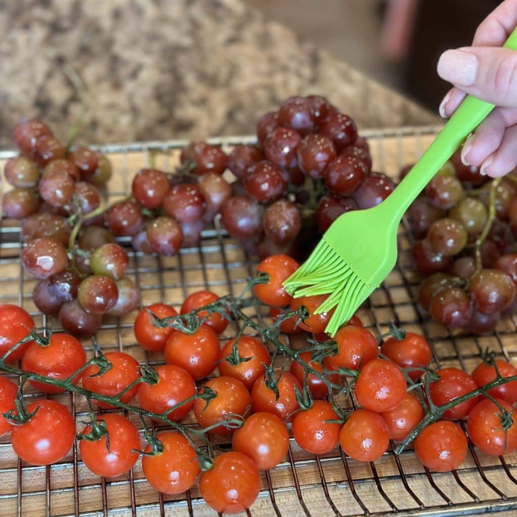 Brushing olive oil on tomatoes and grapes.
