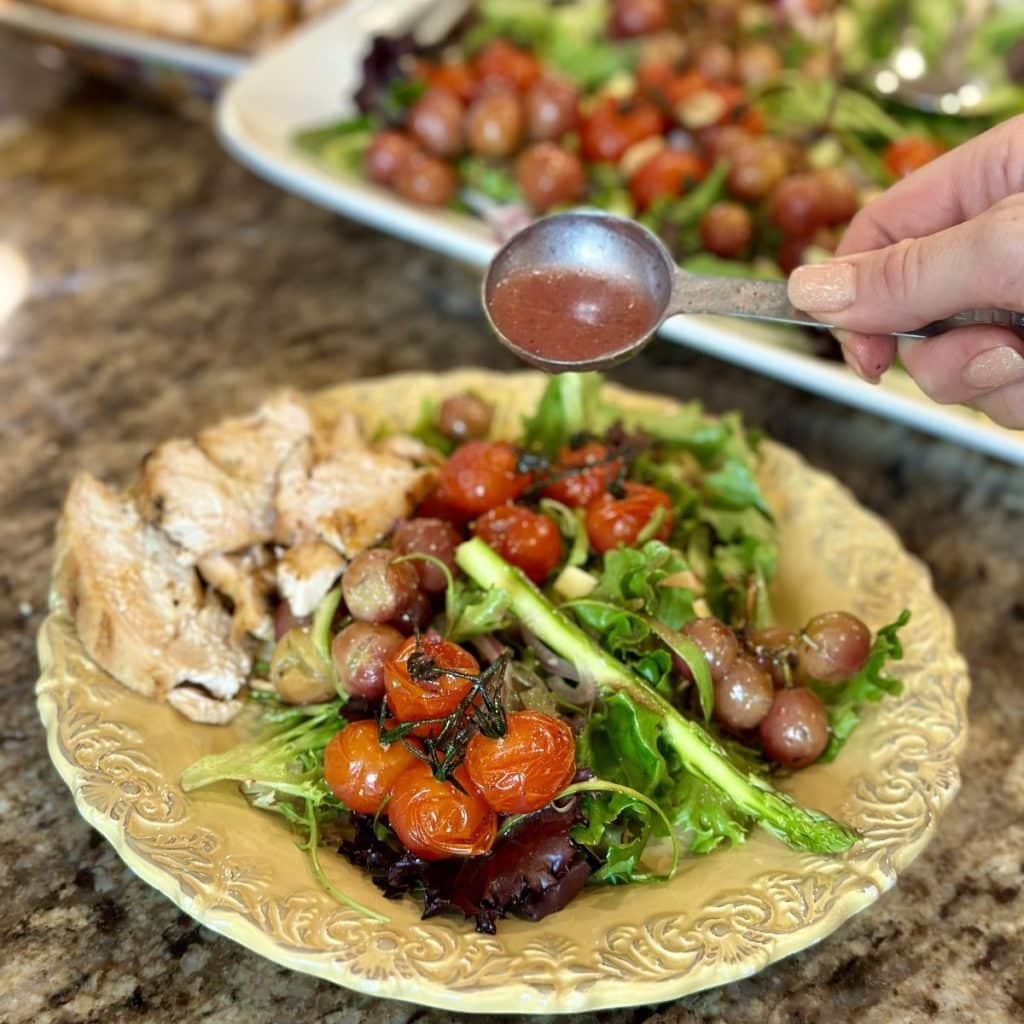 Pouring dressing on a small plate of salad.