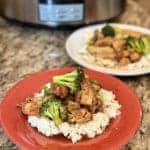 A plate of rice topped with teriyaki chicken and broccoli.