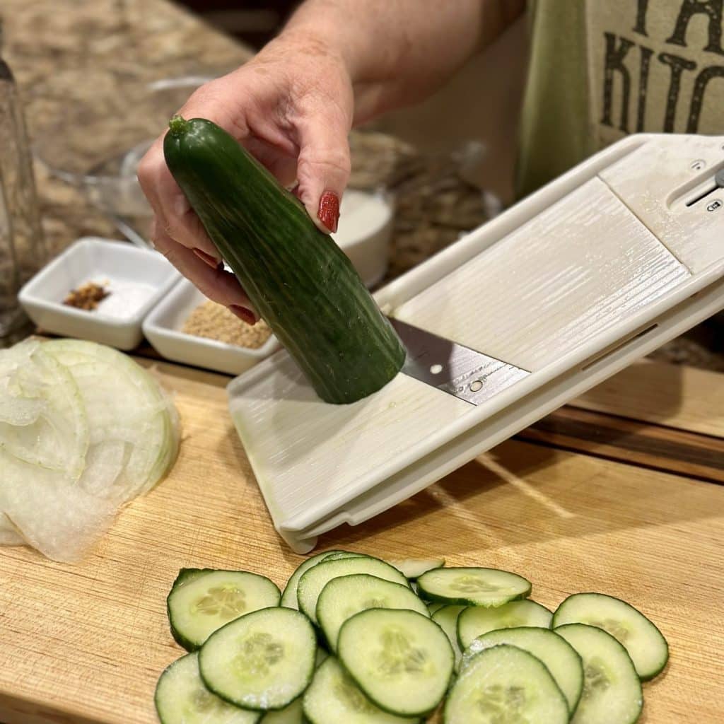 Thinly slicing cucumbers on a mandolin.