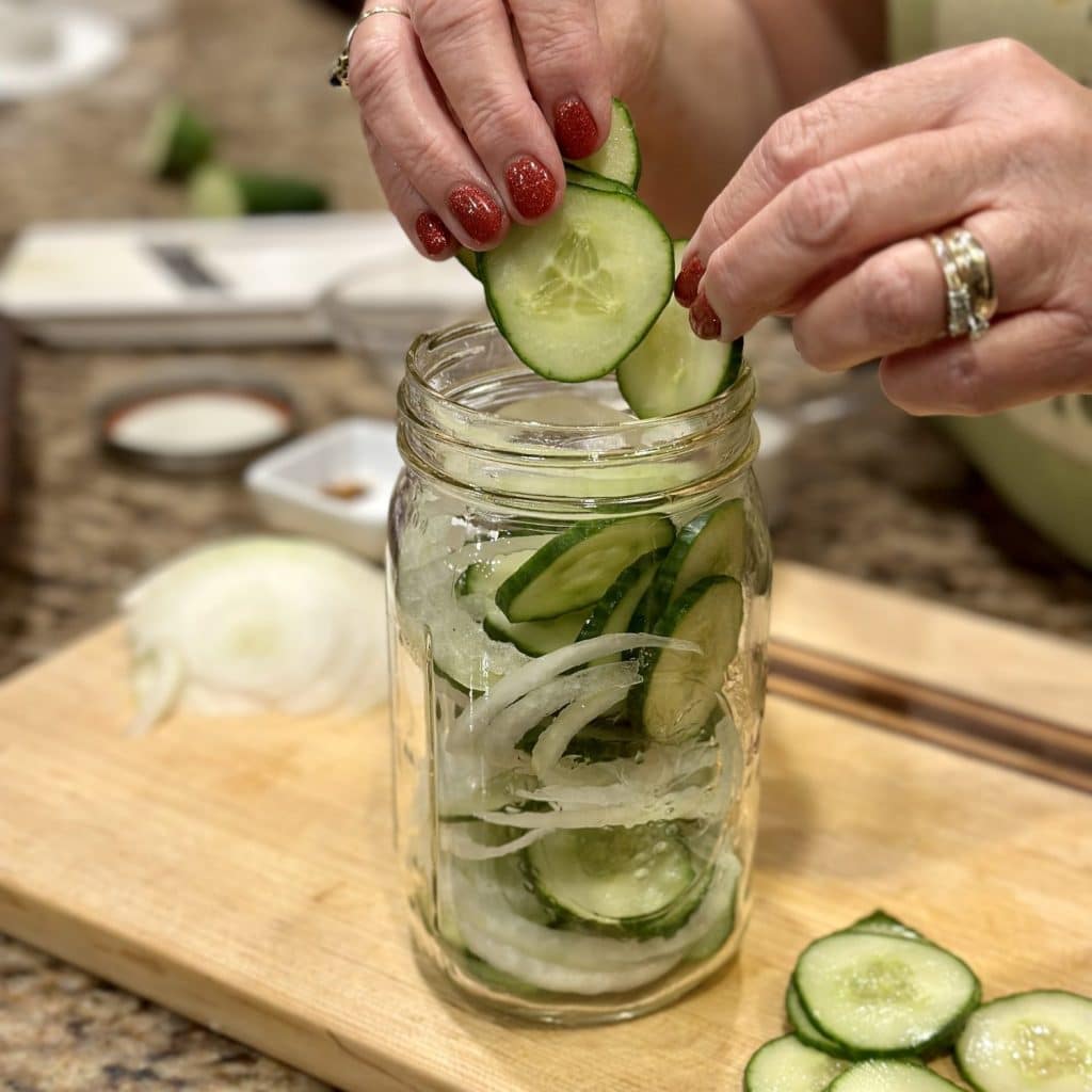 Packing cucumbers and onions in a glass jar.