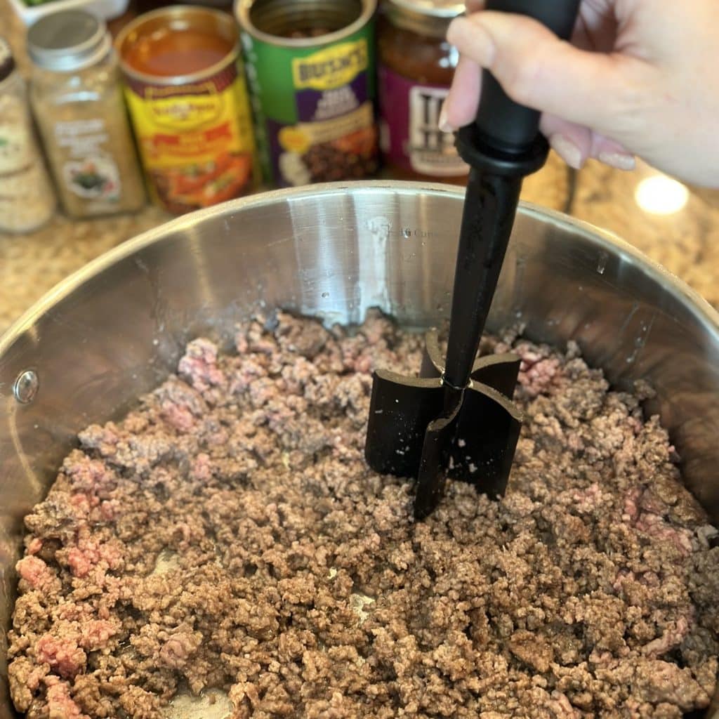 Breaking up ground beef in a skillet.