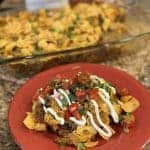 A plate topped with Frito taco pie, sour cream and pico de gallo.