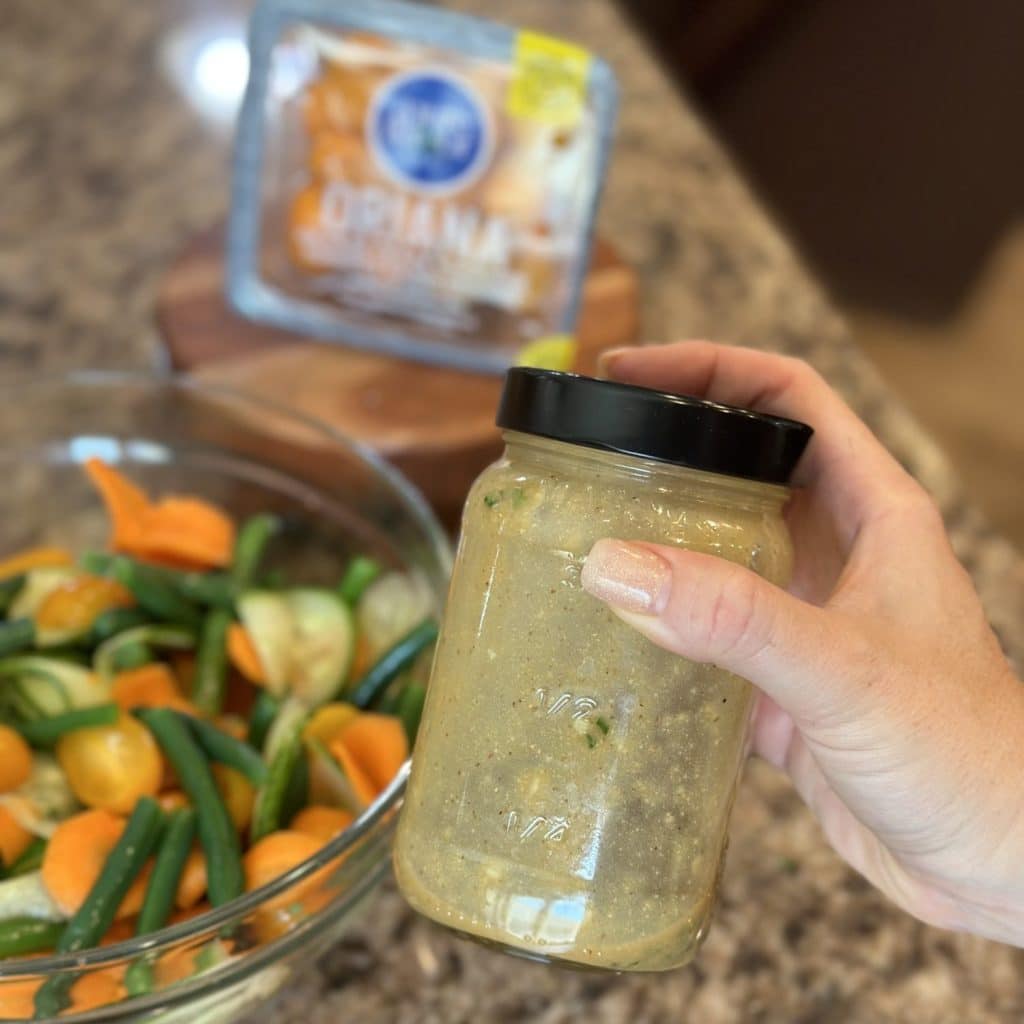 Shaking the ingredients for a dressing inside a glass jar.