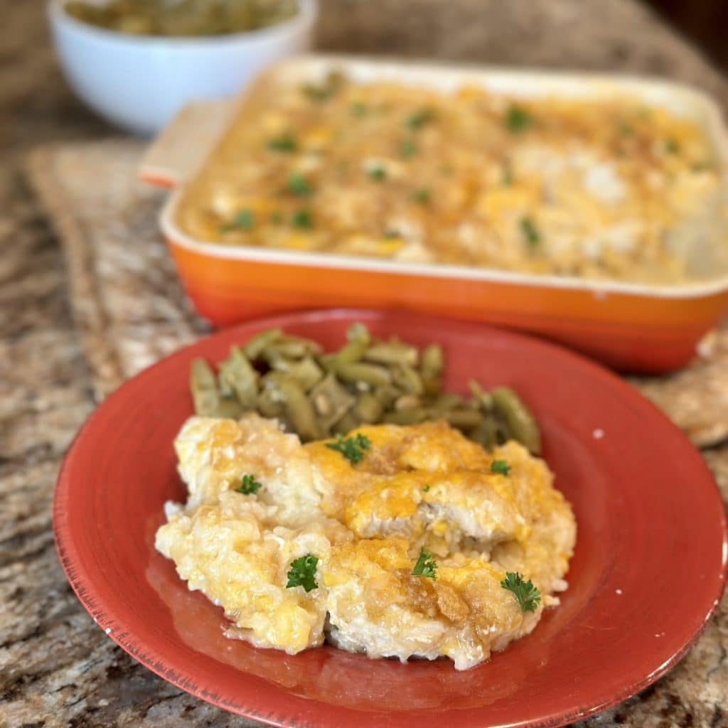 A serving of chicken and rice casserole on a plate with green beans.
