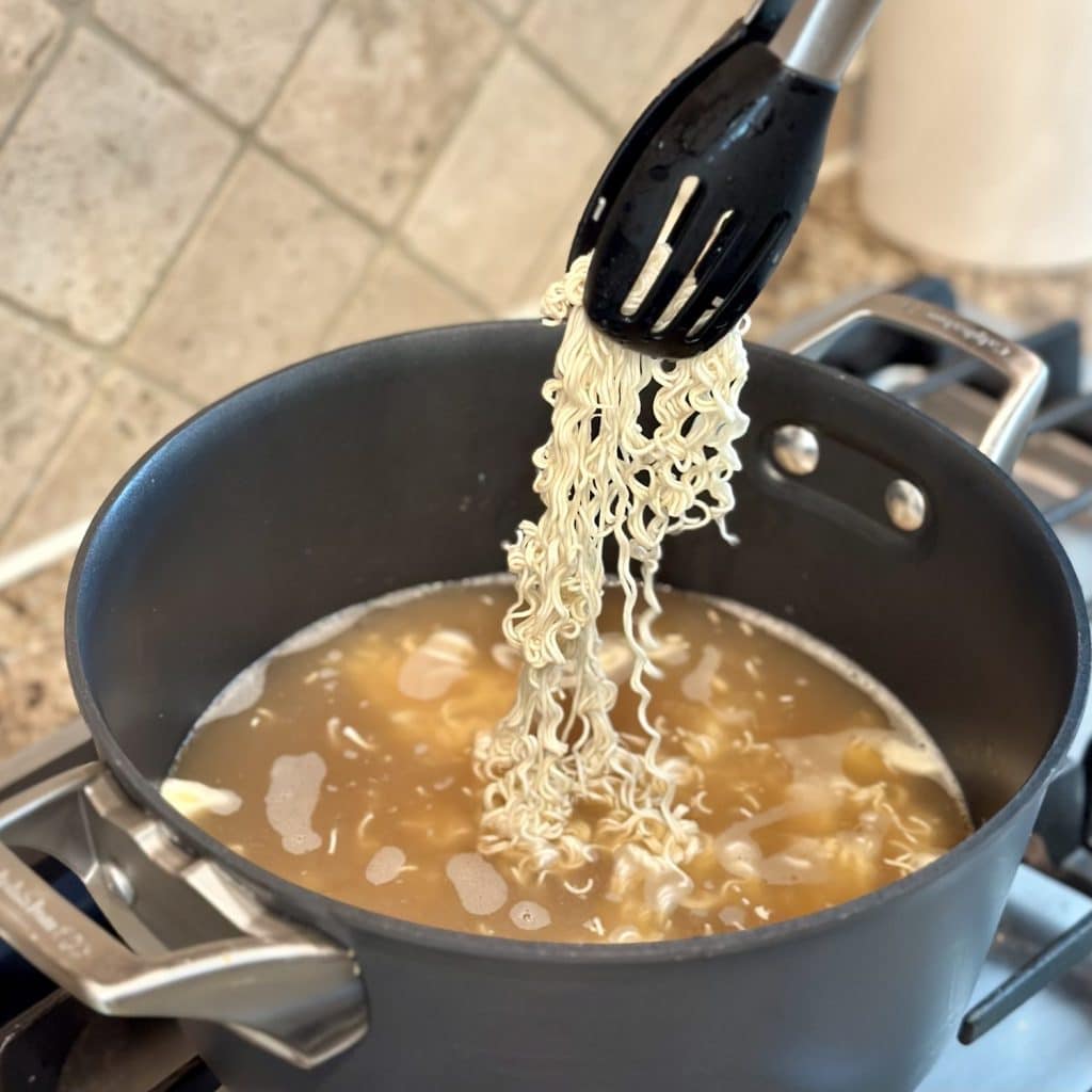 Cooking ramen noodles in a pot of broth.
