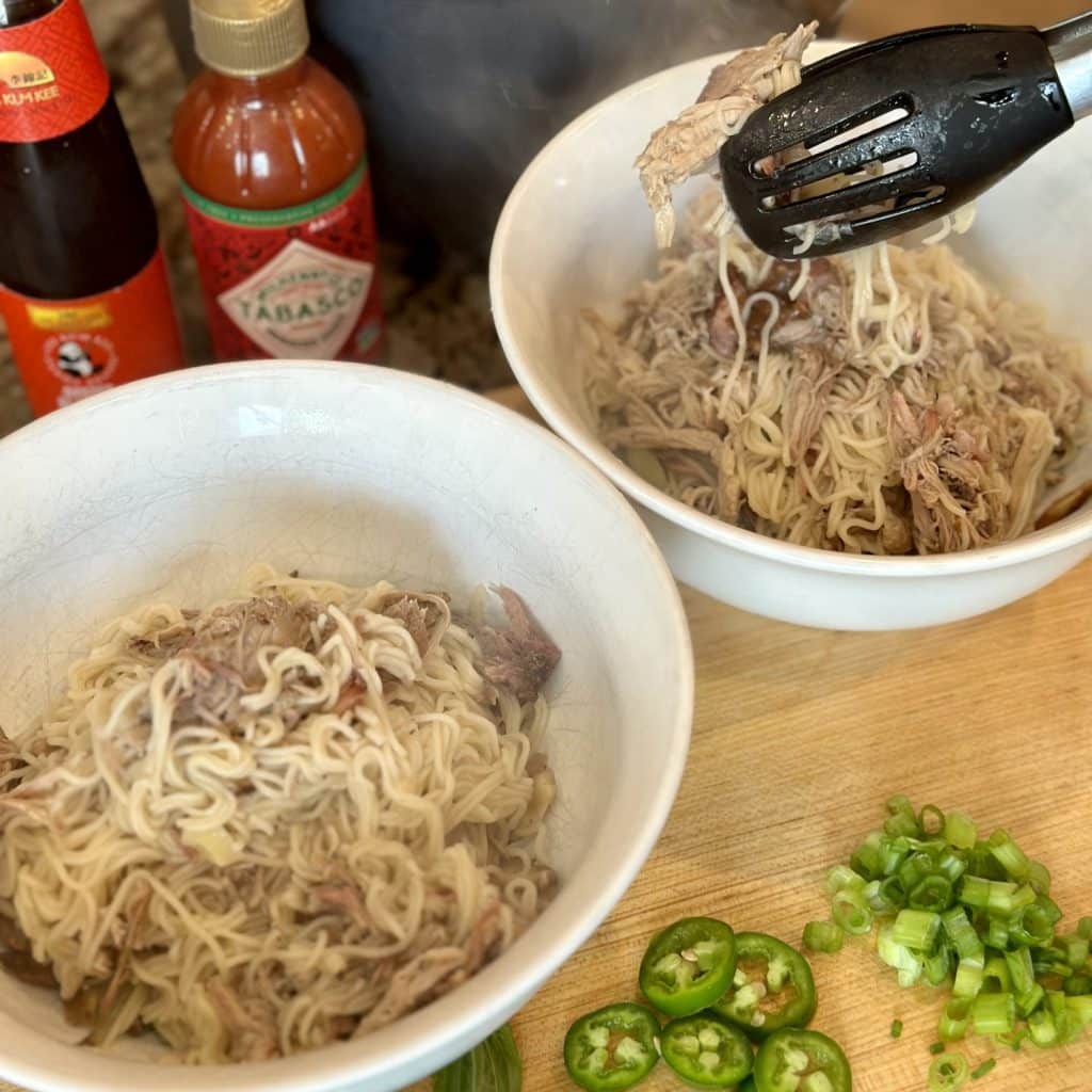 Placing cooked ramen and meat in servings bowls.