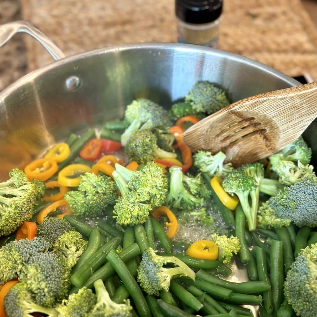 Stirring together a blend of vegetables in a skillet.