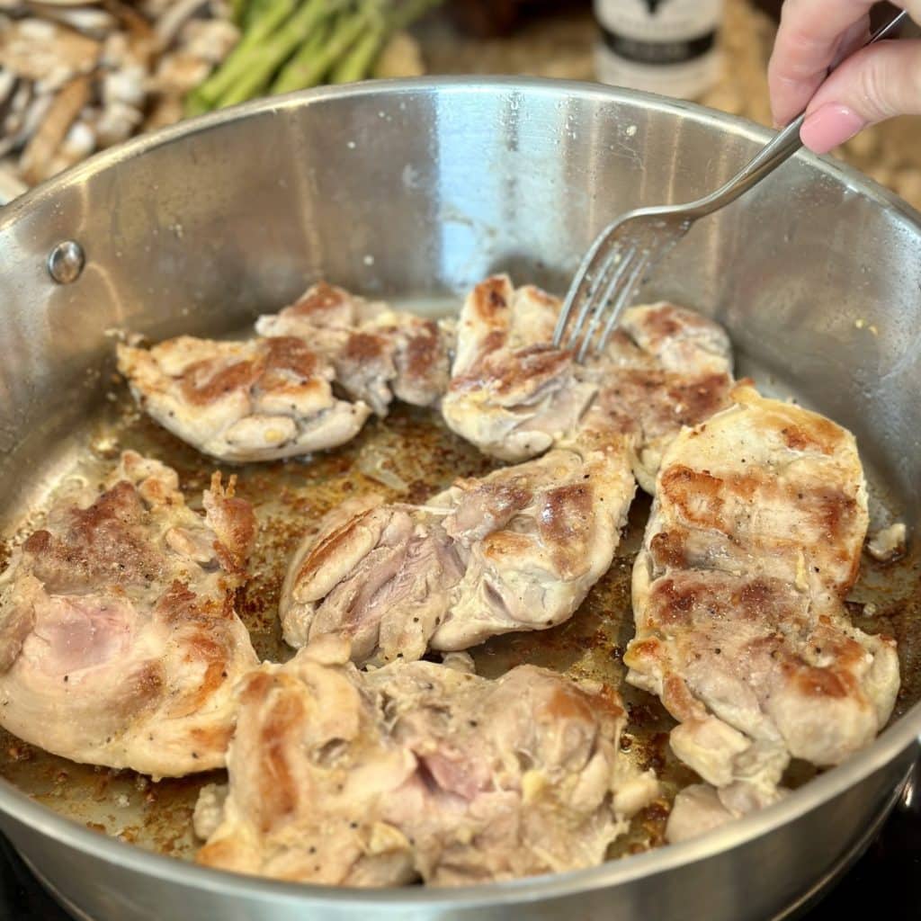 Cooking chicken thighs in a skillet.