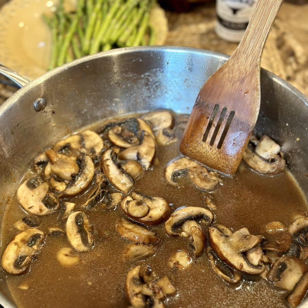 Stirring mushrooms and broth in a skillet.