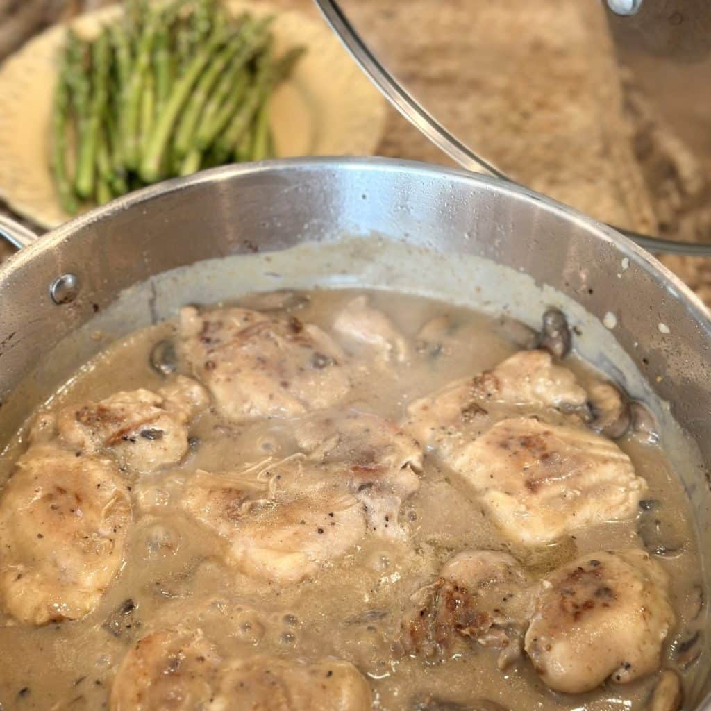 Simmering chicken thighs in gravy in a skillet.