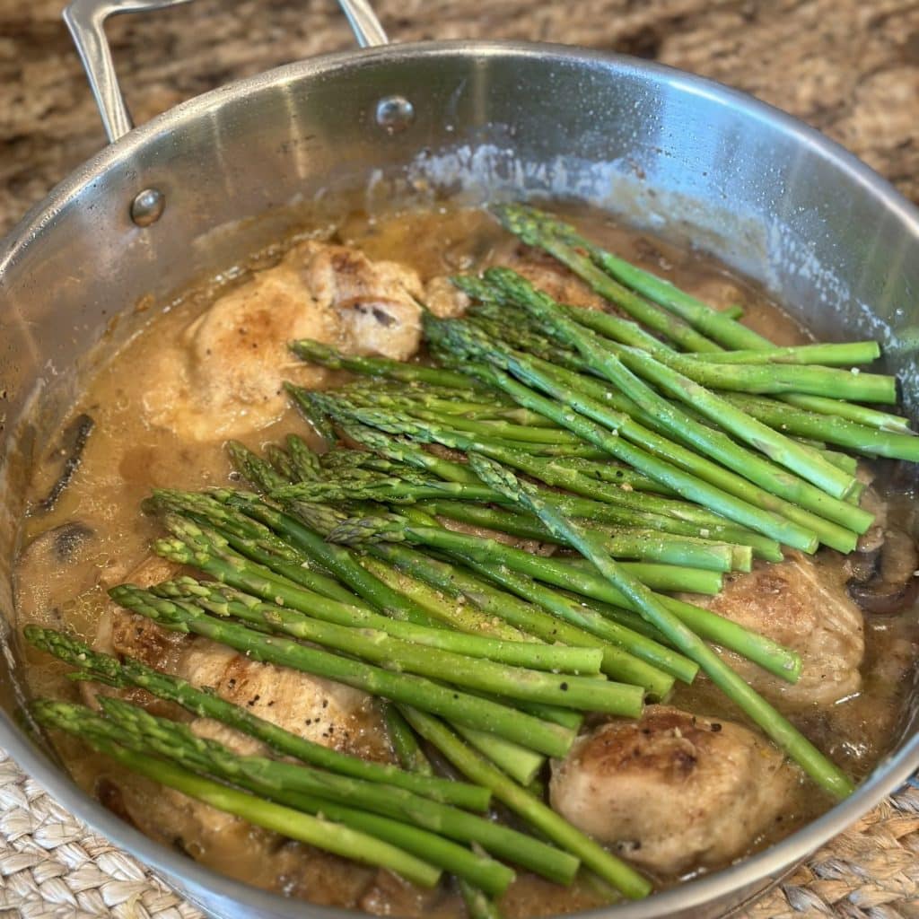Vegetables and chicken cooking in a skillet.