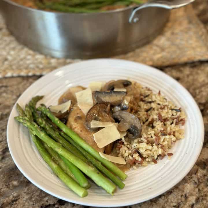 A plate topped with vegetables, ancient grains, chicken and gravy.