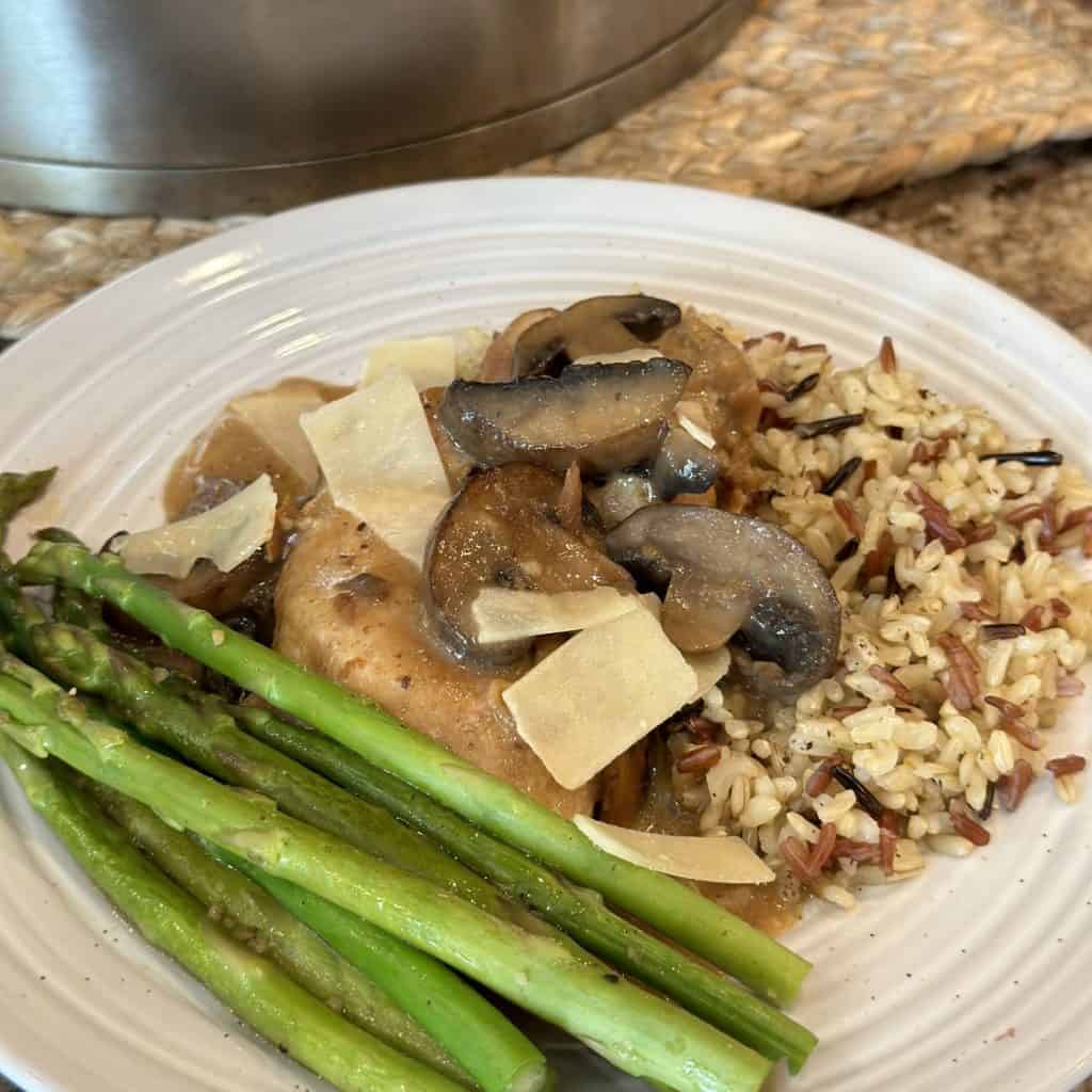 A close up shot of asparagus, chicken, mushrooms, gravy and grains.
