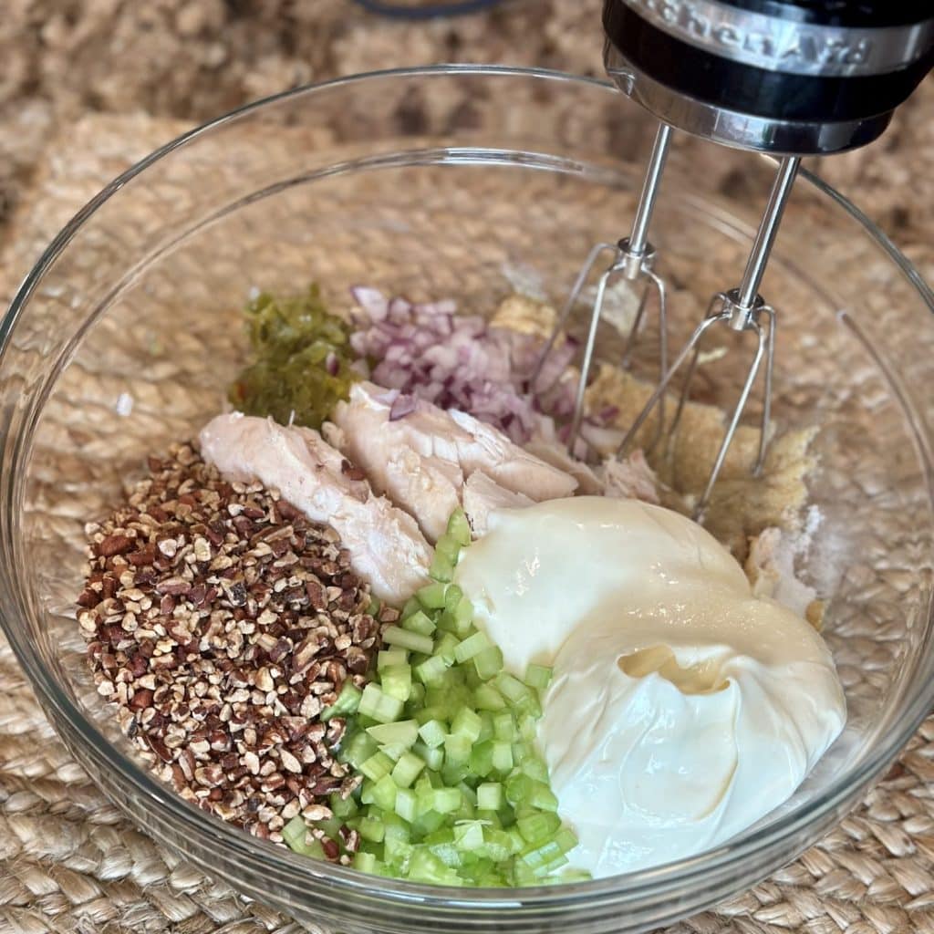 Mixing together chicken salad ingredients in a bowl.