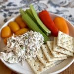 A plate of chicken salad, crackers and veggies.