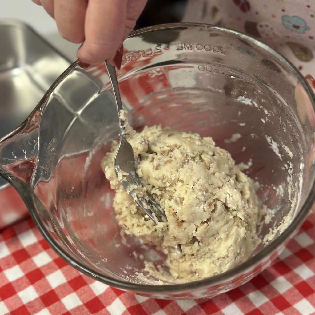 Mixing together a shortbread crust in a bowl.