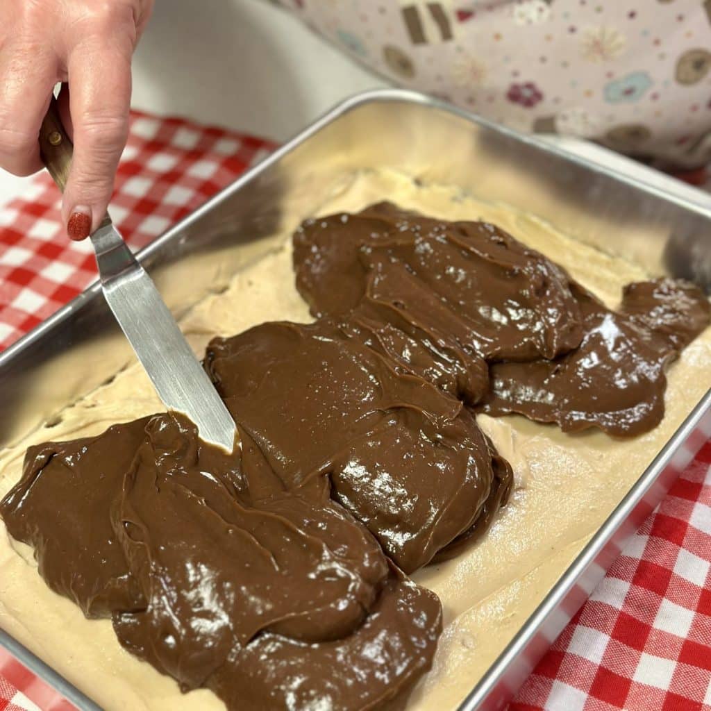 Spreading chocolate pudding on a layered dessert.