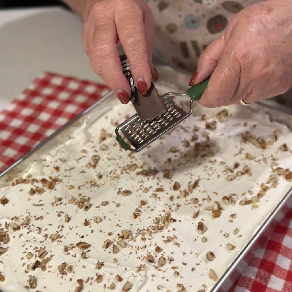 Adding chocolate shavings on top of a whipped cream topped dessert.