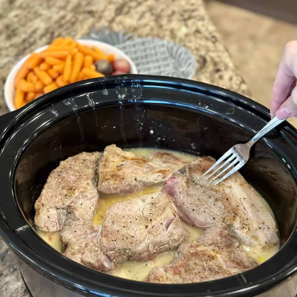 Adding ribs to a crockpot with soup and broth.