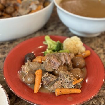 A completed dinner plate of pork ribs, gravy and vegetables.