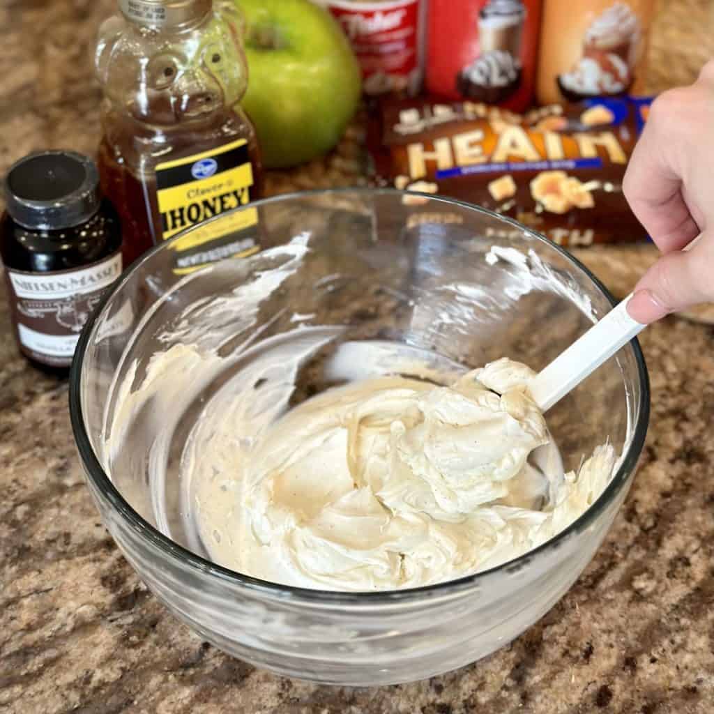 Mixing together cream cheese in a bowl.