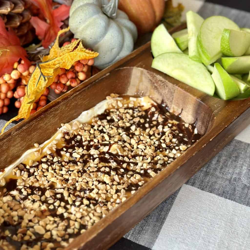 Cream cheese topped with caramel and chocolate served with apple slices