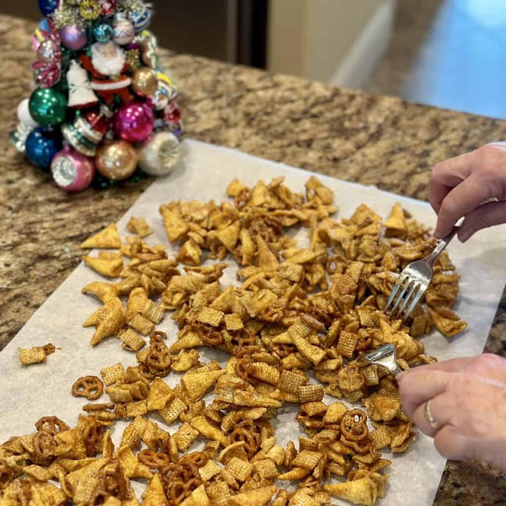 Breaking apart caramel Chex mix on parchment paper.