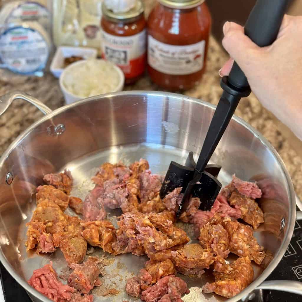 Crumbling up ground beef in a skillet.