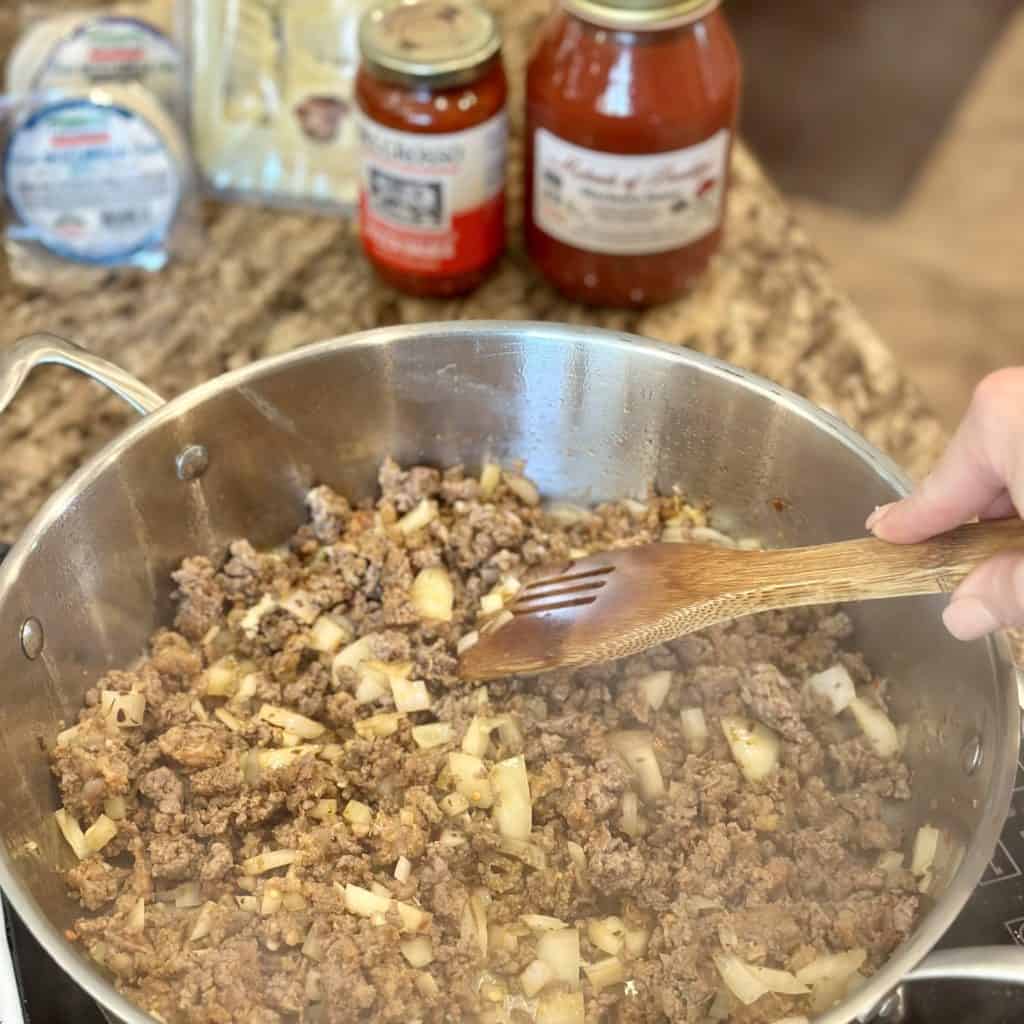 Mixing garlic, onion and ground beef in a skillet.